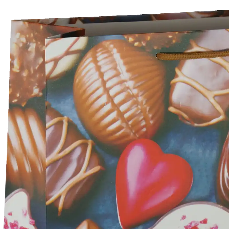 Zbliżenie na górną część torebki, ukazujące strukturę nadruku pralin oraz fragment brązowego sznurkowego uchwytu.
