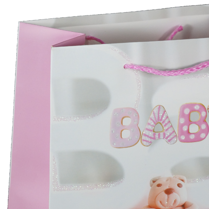 Zbliżenie na górną część różowej torebki prezentowej z tasiemkami i ozdobnym nadrukiem literowym BABY.