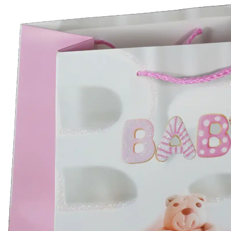 Zbliżenie na górną część różowej torebki prezentowej z tasiemkami i ozdobnym nadrukiem literowym BABY.