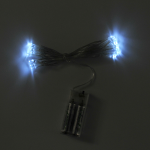 Zbliżenie na świecące ozdoby i lampki LED po włączeniu. Ciepłe białe światło oraz widoczny mechanizm zasilania bateryjnego.