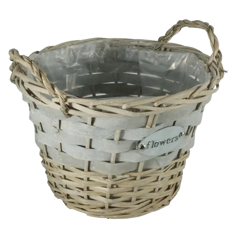 Zbliżenie na plecioną strukturę szarej wikliny oraz uchwyty. Wyraźnie widoczna wewnętrzna folia ochronna oraz metalowa tabliczka z napisem Flowers.