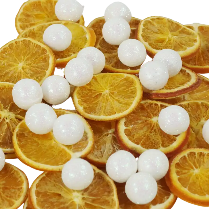Styropianowe kulki z brokatem umieszczone pomiędzy plastrami suszonej pomarańczy. Dekoracja o świątecznym charakterze do wykorzystania w stroikach.
