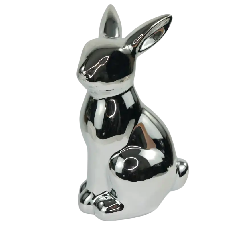 Srebrna figurka zająca ceramicznego w widoku z półprofilu. Dekoracja wiosenna o gładkiej, błyszczącej powierzchni.