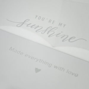 Zbliżenie na wieczko białego flowerboxa z ozdobnym napisem You are my sunshine oraz dopiskiem Made everything with love.