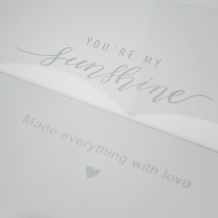Zbliżenie na wieczko białego flowerboxa z ozdobnym napisem You are my sunshine oraz dopiskiem Made everything with love.