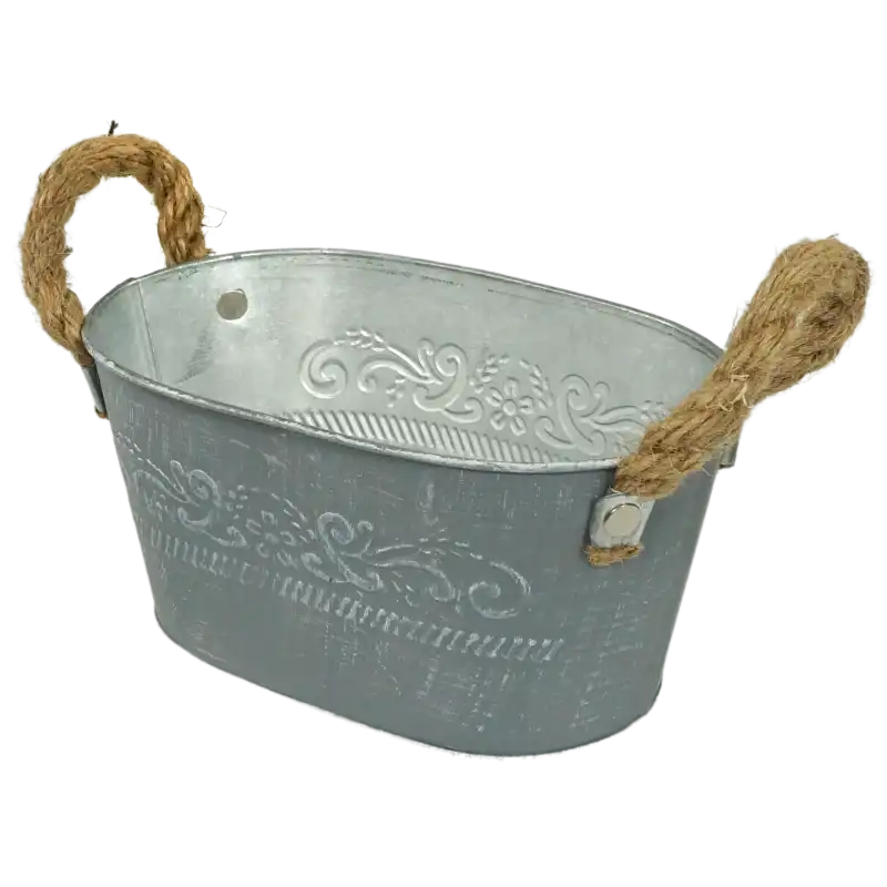 Metalowa osłonka 18 cm w ujęciu pod kątem. Widoczny owalny kształt, postarzana powierzchnia w kolorze szarym oraz dekoracyjne zdobienia roślinne.