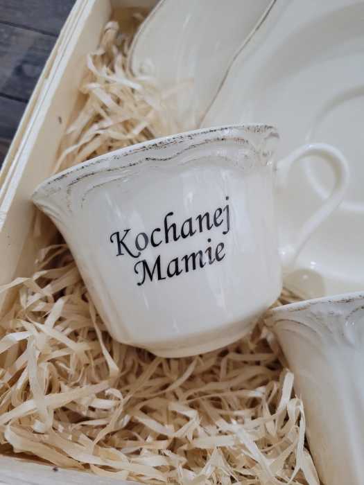Zbliżenie na jedną z filiżanek z napisem Kochanej Mamie umieszczoną w ozdobnym koszyku.