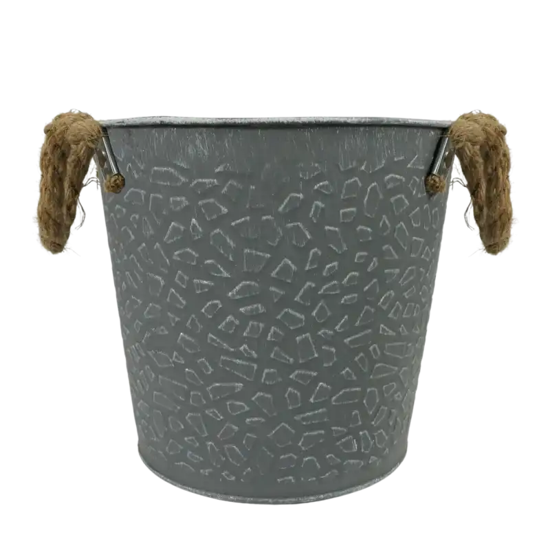 Metalowa osłonka szara o średnicy 18 cm. Dekoracyjna doniczka w postarzanym stylu posiada tłoczony wzór na bokach oraz praktyczne uchwyty wykonane z jutowego sznura.