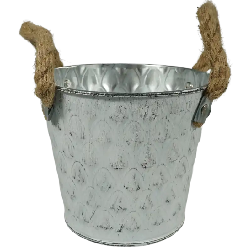 Biała metalowa osłonka na kwiaty w kształcie wiaderka o średnicy 14 cm. Posiada ozdobne uchwyty ze sznura i postarzany wzór, idealna do dekoracji wnętrz.