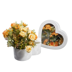 Kompozycja z welurowym flowerboxem wypełnionym pomarańczowymi kwiatami. Obok widoczna przezroczysta pokrywka, która pozwala na bezpieczne zamknięcie pudełka przy zachowaniu pełnej ekspozycji dekoracji.