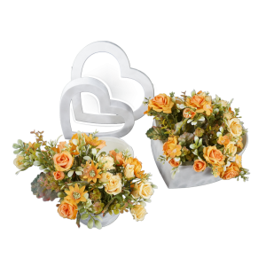Dwa welurowe flowerboxy w kształcie serc wypełnione sztucznymi kwiatami w odcieniach pomarańczu. Ujęcie z boku prezentuje estetykę wykonania pudełek oraz ich praktyczne zastosowanie w dekoracji.