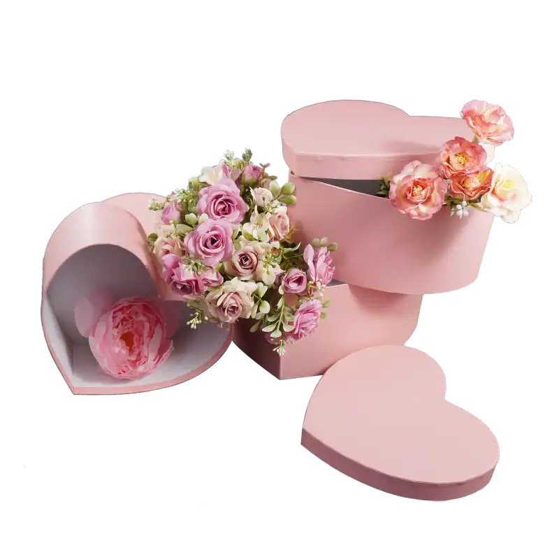 Kompozycja z różowych flowerboxów w kształcie serca wypełnionych bukietami różowych kwiatów. Pokrywki leżą obok.