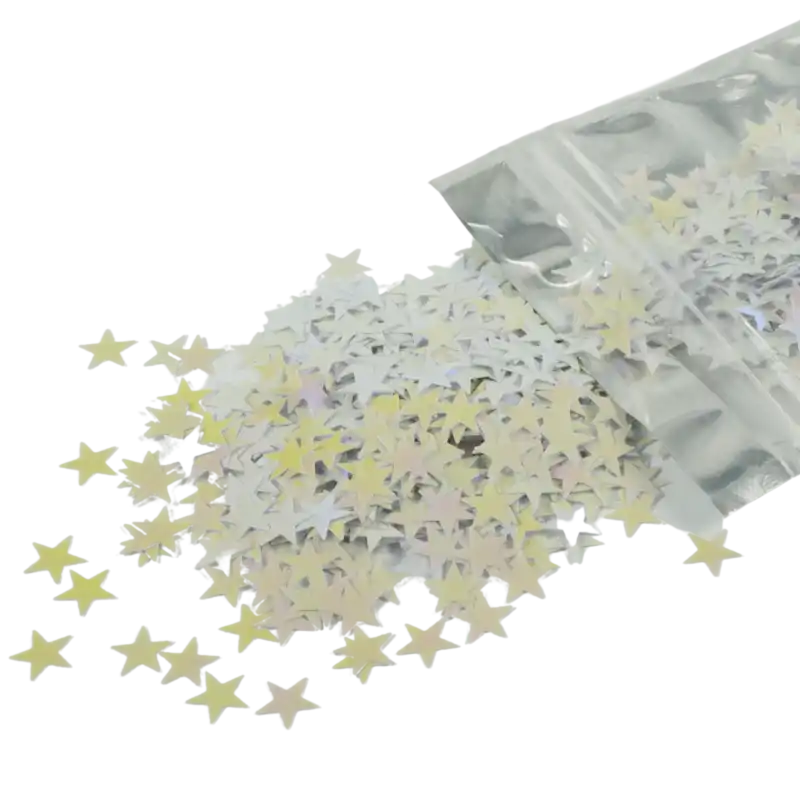 Confetti gwiazdki 20 g o rozmiarze 1 cm rozsypane na powierzchni, wysypujące się z foliowego opakowania. Dekoracja zmieniająca barwę od bieli po róż.