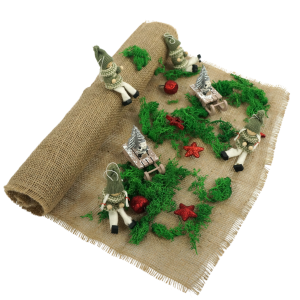 Tkanina jutowa wykorzystana jako tło do świątecznej dekoracji z mchem, figurkami krasnali i małymi saniami. Naturalna juta o szerokości 48 cm stanowi bazę dla kompozycji.