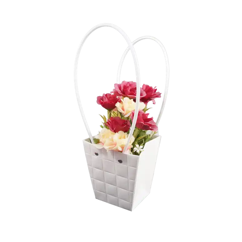 Kompozycja kwiatowa w białej torebce prezentowej o wysokości 32 cm, ujęta z profilu dla podkreślenia formy i uchwytów.