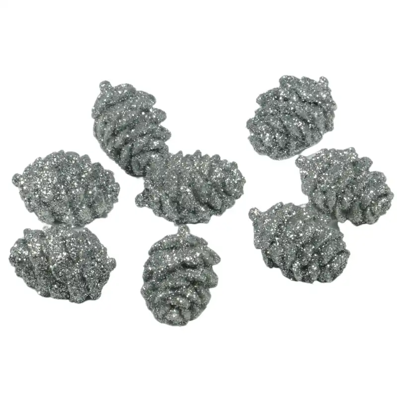 Komplet 8 srebrnych szyszek dekoracyjnych o wymiarach 3x2 cm. Elementy pokryte mieniącym się brokatem posiadają płaską stronę, co ułatwia ich stabilne ułożenie w kompozycjach.