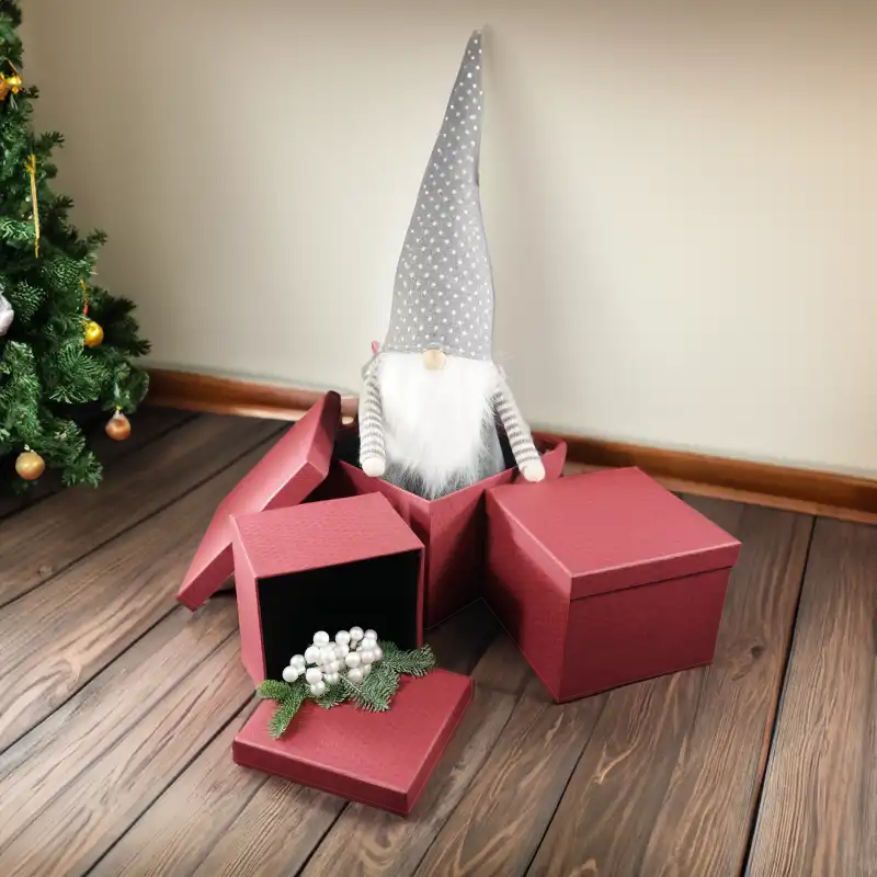 Zestaw bordowych flowerboxów z pokrywkami w aranżacji bożonarodzeniowej na drewnianym podłożu przy choince.
