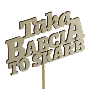 Zbliżenie na drewniany napis Taka babcia to skarb umieszczony na długim patyczku. Dekoracja pokazana pod kątem, podkreślającym fakturę naturalnego drewna i precyzyjne wycięcie liter.
