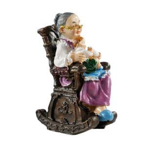 Widok figurki babci w fotelu z profilu, ukazujący detale antycznego wykończenia mebla oraz postać trzymającą butelkę.