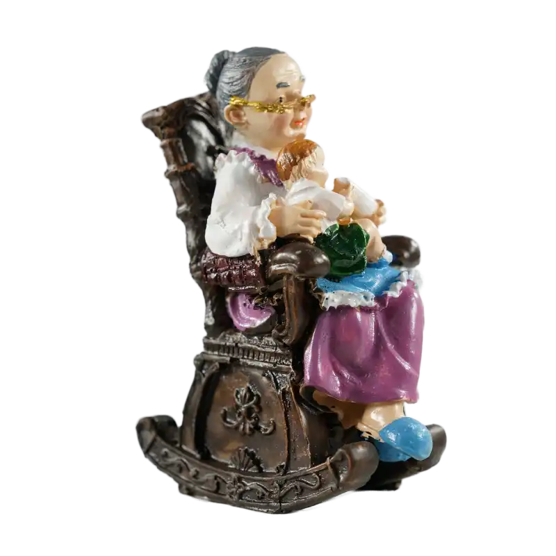 Widok figurki babci w fotelu z profilu, ukazujący detale antycznego wykończenia mebla oraz postać trzymającą butelkę.