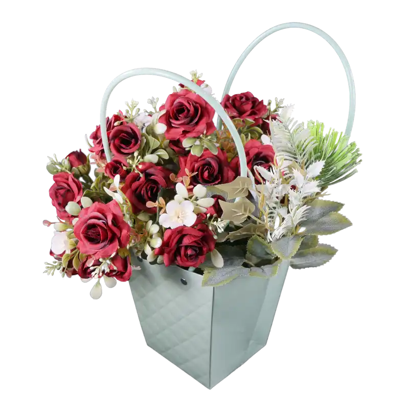 Pikowana torebka na kwiaty w odcieniu mięty, wyeksponowana w ujęciu z góry pod kątem. Wnętrze torebki wypełniają czerwone róże oraz zielone dodatki florystyczne.
