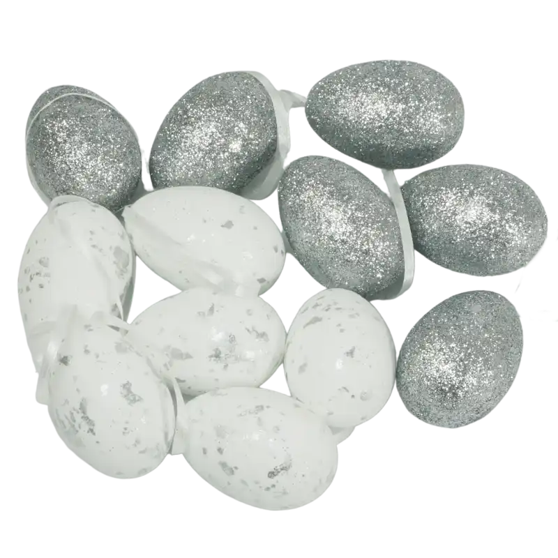 Zestaw 12 wielkanocnych zawieszek w kształcie pisanek o wymiarach 5,5 cm x 4 cm. Styropianowe jajka zdobione srebrnym brokatem i nakrapianym wzorem, wyposażone w praktyczne wstążeczki do zawieszenia.