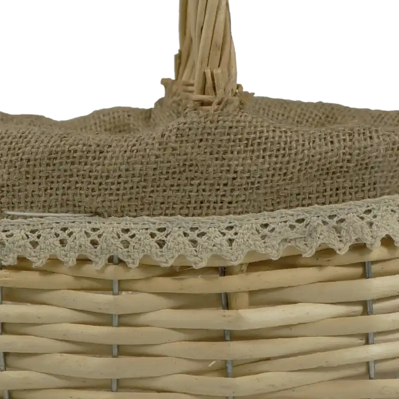 Zbliżenie na górną krawędź kosza wiklinowego z naturalnym jutowym materiałem oraz ozdobną, ażurową koronką.