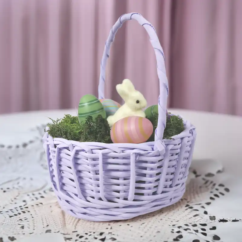 Aranżacja wielkanocna w fioletowym koszyku wiklinowym, ustawiona na białej serwecie, widok z profilu.