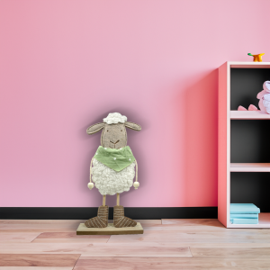 Filcowa owieczka chłopiec 37 cm zaaranżowana w pokoju dziecięcym, ustawiona na podłodze przy różowej szafce.