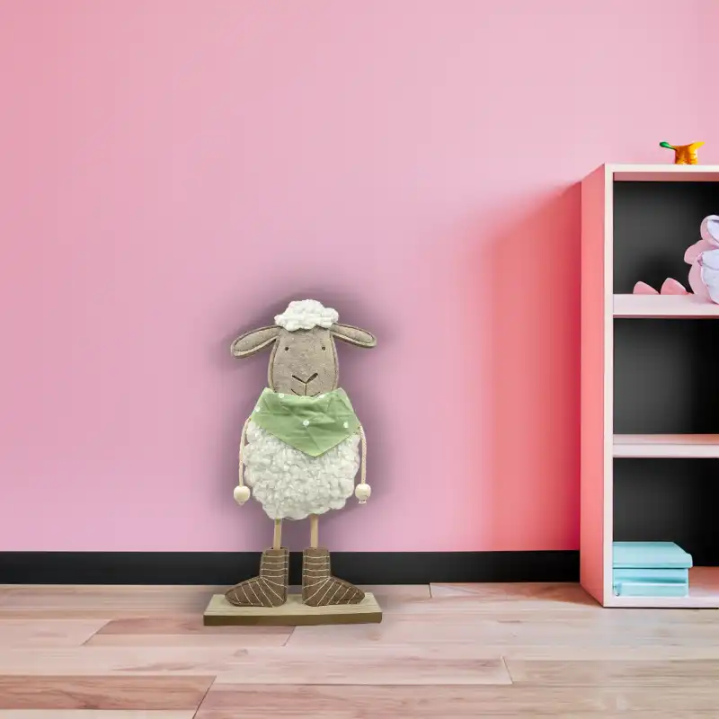 Filcowa owieczka chłopiec 37 cm zaaranżowana w pokoju dziecięcym, ustawiona na podłodze przy różowej szafce.