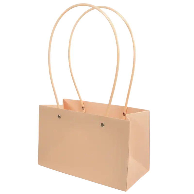 Łososiowa papierowa torebka na kwiaty 35x22 cm z dwoma uchwytami, ukazana w ujęciu z półprofilu, prezentująca estetyczną formę opakowania prezentowego.