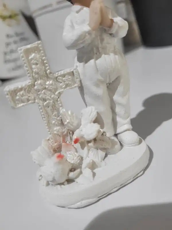 Zbliżenie na podstawę figurki przedstawiającą krzyż ozdobiony gołębiami, wykonane z dbałością o każdy detal.