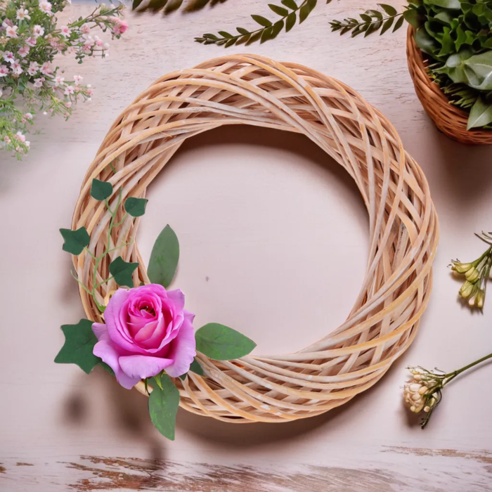 Wiklinowy wianek 35 cm ozdobiony pojedynczą różową różą z zielonymi liśćmi. Naturalny dodatek do wnętrz, idealny na drzwi lub jako element większych kompozycji.