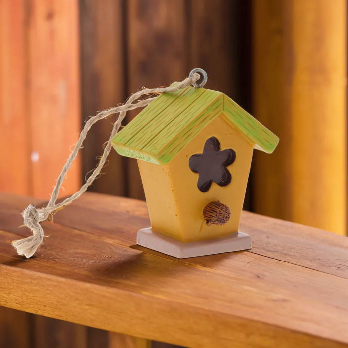 Zawieszka budka dla ptaków o wymiarach 5,5x5x3 cm w kolorze żółto-zielonym. Dekoracja posiada jutowy sznurek i ozdobny kwiatowy otwór, idealna do wnętrz.