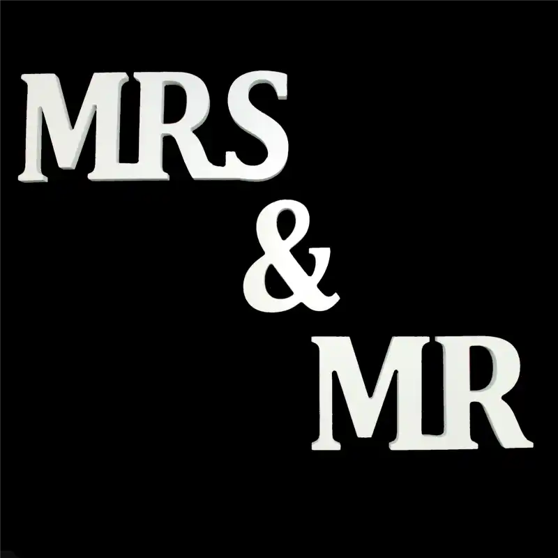 Biały napis Mr &amp; Mrs z tworzywa o wysokości 9 cm i długości 50 cm. Eleganckie artykuły dekoracyjne na wesele, widoczne w układzie pionowym na czarnym tle.