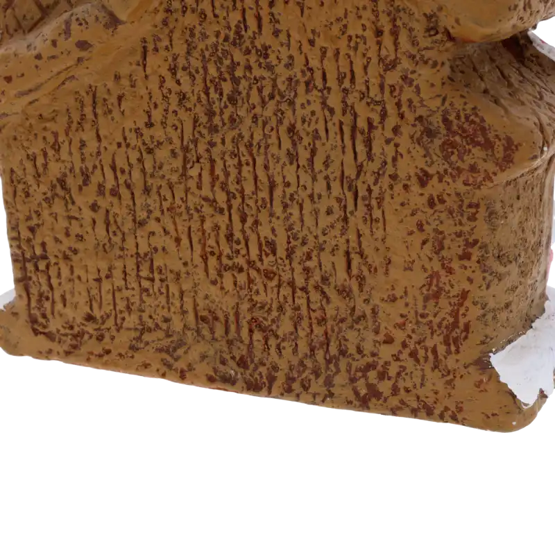 Zbliżenie na boczną ściankę ceramicznej ozdoby. Faktura materiału przypomina naturalnie pieczone ciasto piernikowe, co nadaje dekoracji realizmu.
