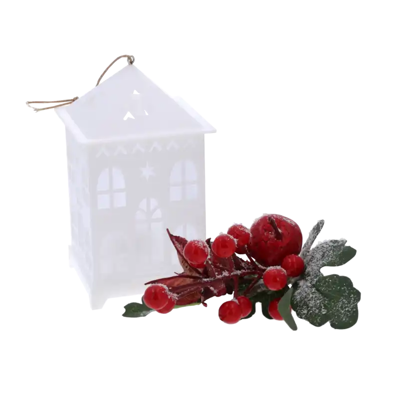 Biały lampion LED w kształcie domku ustawiony obok dekoracyjnej gałązki z czerwonymi owocami, tworzący świąteczną kompozycję na Boże Narodzenie.