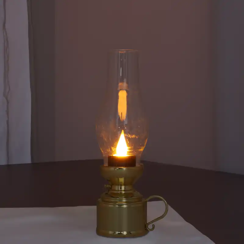 Złota lampa naftowa LED 19 cm ustawiona na blacie. Efekt migającego światła doskonale naśladuje blask palącej się świecy, idealnie pasując do świątecznej aranżacji.