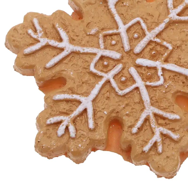 Zbliżenie na fakturę zawieszki piernikowej śnieżynki. Widoczne precyzyjne zdobienia imitujące biały lukier na brązowej, porowatej powierzchni.