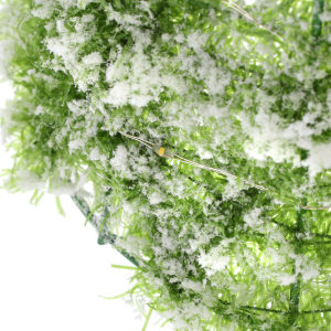 Detail oświetlenia LED wplecionego w ośnieżone, zielone gałązki choinki, podkreślający ciepłą barwę światła oraz strukturę sztucznego śniegu na dekoracji.