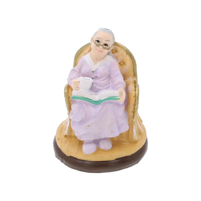 Figurka babcia z filiżanką i książką o wysokości 7 cm w fioletowej sukni, siedząca w fotelu. Detal prezentuje postać w okularach, idealna dekoracja na prezent.