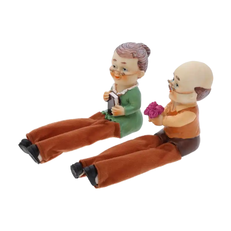 Widok z profilu na figurki babci i dziadka 10 cm. Postacie siedzą obok siebie, dziadek trzyma bukiet róż, babcia trzyma książkę.