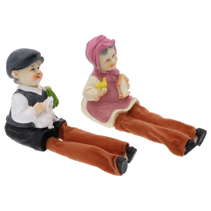 Ujęcie z boku przedstawiające siedzące figurki dziadka i babci z luźno opadającymi materiałowymi nogawkami.