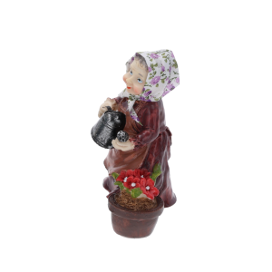Figurka babcia z konewką widziana pod kątem. Ujęcie eksponuje wyraz twarzy, chustkę z tkaniny oraz kwiaty w doniczce. Dekoracja 15 cm pasująca do różnych stylów wnętrz.