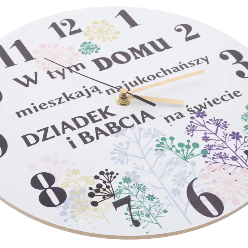 Zbliżenie na tarczę zegara pod kątem, ukazujące nadruk dedykacji, kwiatowe zdobienia oraz wskazówki czasomierza.