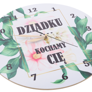 Zbliżenie na tarczę zegara z napisami i motywem roślinnym, pokazujące szczegóły nadruku oraz wskazówki mechanizmu.