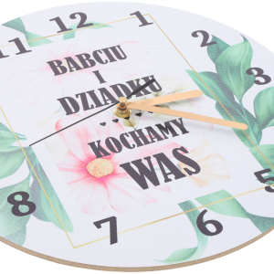 Zbliżenie na tarczę zegara z personalizowanym napisem i złotymi wskazówkami. Widoczny detal kwiatowej grafiki.