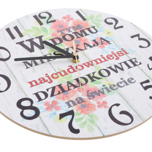 Zbliżenie na tarczę zegara z płyty MDF, pokazujące czarne wskazówki oraz ozdobny napis i kwiatowy nadruk.