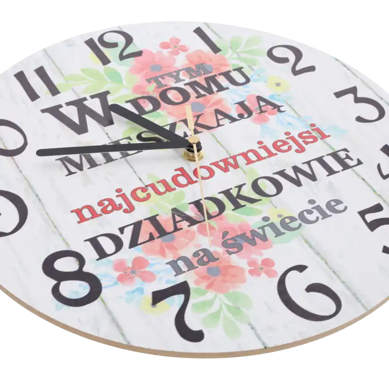 Zbliżenie na tarczę zegara z płyty MDF, pokazujące czarne wskazówki oraz ozdobny napis i kwiatowy nadruk.