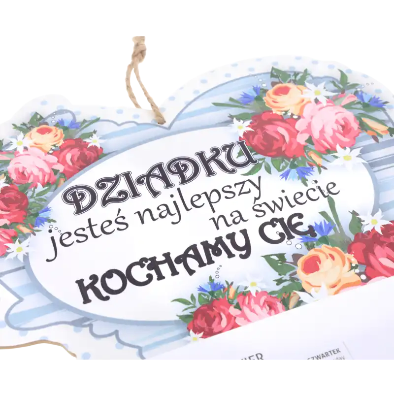 Zbliżenie na dekoracyjną górną część kalendarza z nadrukiem Dziadku jesteś najlepszy na świecie kochamy Cię oraz kolorowymi kwiatami. Widoczny jutowy sznurek do zawieszenia.